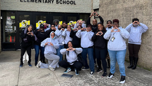 Group of people in front of Seat Pleasant Elementary School making heart shapes with their hands.